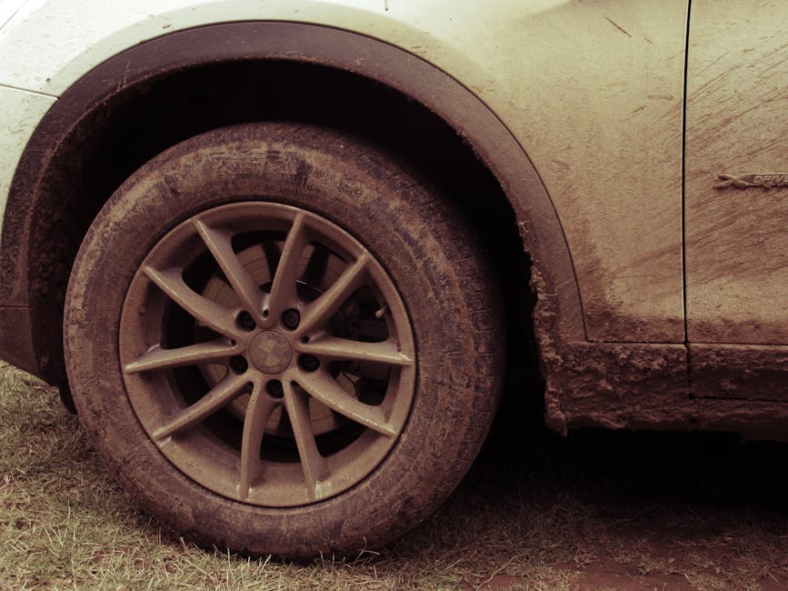 Close-up view of a car wheel covered in mud, highlighting off-road adventures.