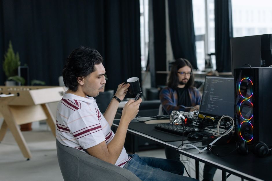Dva programera na poslu u modernom uredu, fokusirani na kodiranje uz kavu